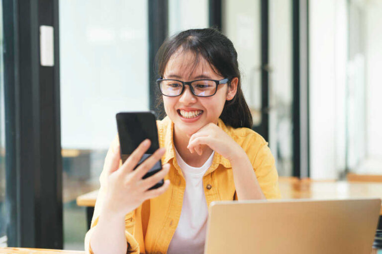 Młoda kobieta patrzy w smartfon i płaci w internecie online
