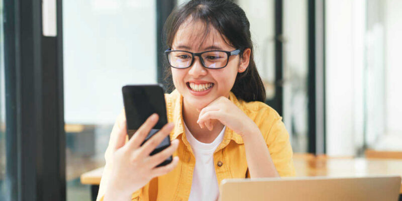 Młoda kobieta patrzy w smartfon i płaci w internecie online